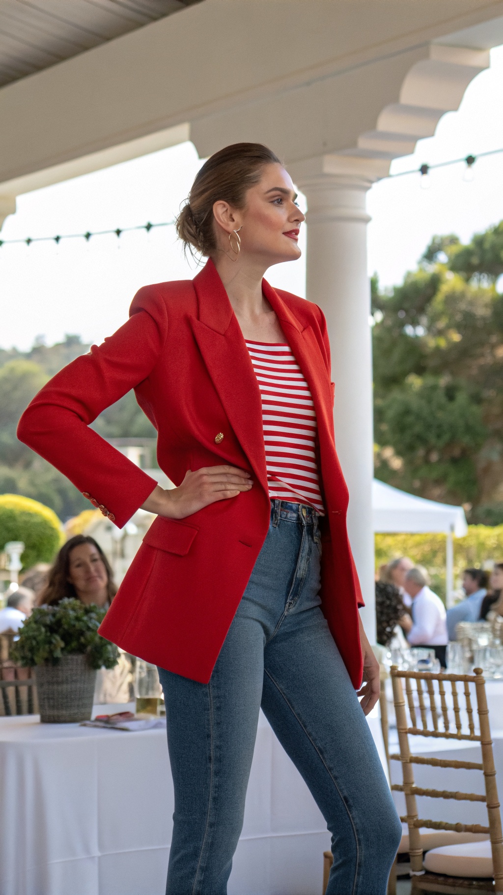 A woman modeling a bright red blazer over a striped top and high-waisted blue jeans, posing confidently.
